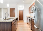 Thumbnail 22 of 30 - A kitchen with a granite countertop and stainless steel appliances.