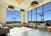 Thumbnail 1 of 21 - A spacious waiting area with grey tiled floors and large windows.