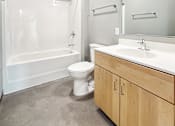 Thumbnail 11 of 22 - A white toilet sits next to a sink in a modern bathroom.