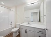 Thumbnail 36 of 58 - A white bathroom with a toilet, sink, and mirror.