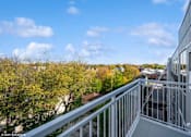 Thumbnail 4 of 58 - A balcony with a metal railing overlooks a cityscape.