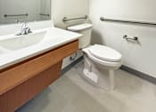 Thumbnail 11 of 21 - A white toilet sits next to a sink in a bathroom.