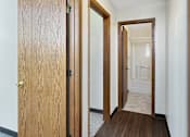 Thumbnail 10 of 20 - A hallway with a wooden floor and two open doors.