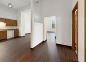 Thumbnail 6 of 20 - A long hallway with a brown floor and white walls.