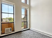 Thumbnail 13 of 20 - A room with a carpeted floor and two large windows.