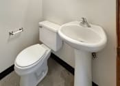 Thumbnail 9 of 20 - A white toilet and sink in a small bathroom.