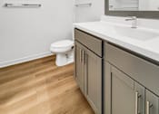 Thumbnail 7 of 37 - A white toilet sits in a bathroom with a wooden floor and a mirror above a sink.