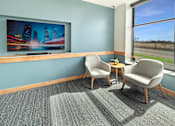 Thumbnail 15 of 21 - Two chairs and a table are placed in front of a television in a room.