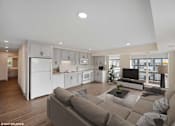Thumbnail 54 of 58 - A modern living room with a grey sofa and a kitchen area in the background.