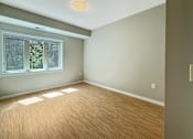 Thumbnail 6 of 20 - A room with a window and wooden flooring.