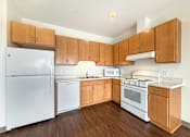 Thumbnail 2 of 21 - A kitchen with wooden cabinets and white appliances.