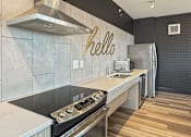 Thumbnail 15 of 31 - A modern kitchen with a stove top oven and a refrigerator.