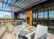 Thumbnail 11 of 31 - A patio with chairs and tables is covered by a roof.