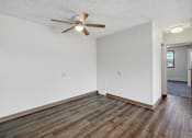 Thumbnail 3 of 12 - A room with a ceiling fan and wooden flooring.