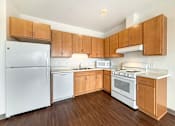 Thumbnail 2 of 21 - A kitchen at The Lumin in the Highland Park neighborhood of St Paul with wooden cabinets and white appliances.