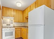 Thumbnail 2 of 12 - A white refrigerator stands in a kitchen with wooden cabinets.