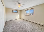 Thumbnail 6 of 12 - A room with a ceiling fan and two windows.