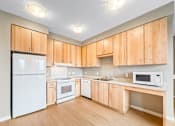 Thumbnail 12 of 22 - A kitchen with wooden cabinets and white appliances.