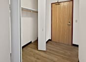 Thumbnail 25 of 29 - A hallway with a wooden door and a white wall.