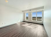 Thumbnail 3 of 21 - A room with wooden flooring and a large window overlooking a field.