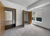 Thumbnail 8 of 35 - A room with a carpeted floor and a window with blinds.