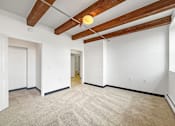 Thumbnail 16 of 34 - A room with a carpeted floor and wooden beams on the ceiling.