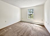 Thumbnail 10 of 16 - A room with a carpeted floor and a window showing trees outside.