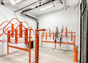 Thumbnail 15 of 37 - A gym with orange equipment and white walls.