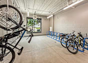 Thumbnail 22 of 22 - A bike is parked on a blue bike rack in a white room.