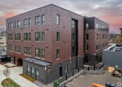 Thumbnail 19 of 37 - a brick apartment building with a sunset in the background