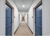 Thumbnail 21 of 37 - a long hallway with blue doors and white walls