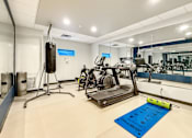 Thumbnail 14 of 37 - A gym with a punching bag, treadmill, and exercise bikes.