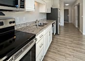 Thumbnail 20 of 31 - A kitchen with a black stove top oven and white cabinets.