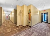 Thumbnail 29 of 34 - A hallway with tan walls and a carpeted floor.