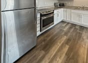 Thumbnail 3 of 31 - A kitchen with a stainless steel refrigerator and wooden floors.