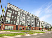 Thumbnail 1 of 22 - A modern multi-story building with a mix of dark and light-colored panels.