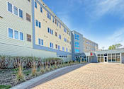 Thumbnail 2 of 20 - A modern building with a brick walkway in front.