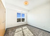 Thumbnail 8 of 21 - A room with a carpeted floor and a window showing a view of a beach.