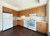 Thumbnail 17 of 21 - A kitchen with white appliances and wooden cabinets.