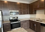 Thumbnail 29 of 31 - A kitchen with brown cabinets and stainless steel appliances.