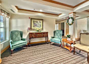 Thumbnail 6 of 16 - A room with a green chair and a wooden table.