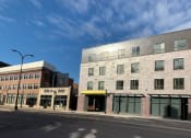 Thumbnail 1 of 37 - a brick building with a silver roof on a city street
