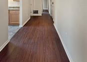 Thumbnail 9 of 15 - A long hallway with wood floors and white walls.