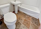 Thumbnail 9 of 12 - A white toilet sits next to a sink in a small bathroom.