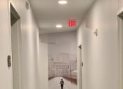 Thumbnail 29 of 37 - a person walking down a hallway with an exit sign on the wall
