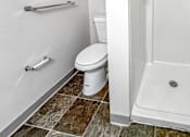 Thumbnail 13 of 40 - A white toilet with a white shower stall with a silver handle.