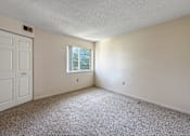 Thumbnail 14 of 40 - A room with a carpeted floor, a window, and a white door.