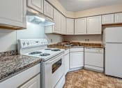 Thumbnail 6 of 40 - A kitchen with white appliances and brown tiled flooring.