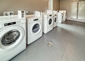 Thumbnail 16 of 22 - A row of white front load washing machines in a laundromat.