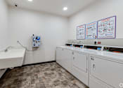Thumbnail 42 of 46 - a laundry room at Stryker Senior Apartments in West St. Paul with two washers and two sinks and a counter with two machines